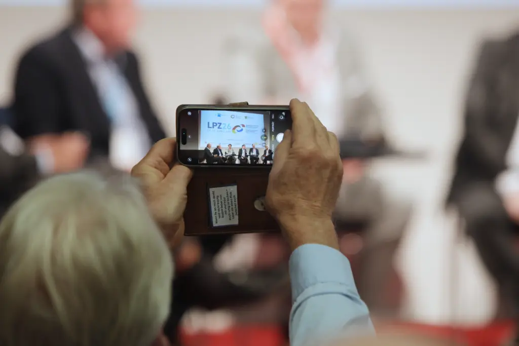 Ein Kongressteilnehmer fotografiert das Panel mit dem Smartphone, auf dessen Display das Logo des 3. Deutsch-Französischen Wirtschaftskongresses Mitteldeutschland (LPZ26) zu sehen ist. Foto: Anja Jungnickel