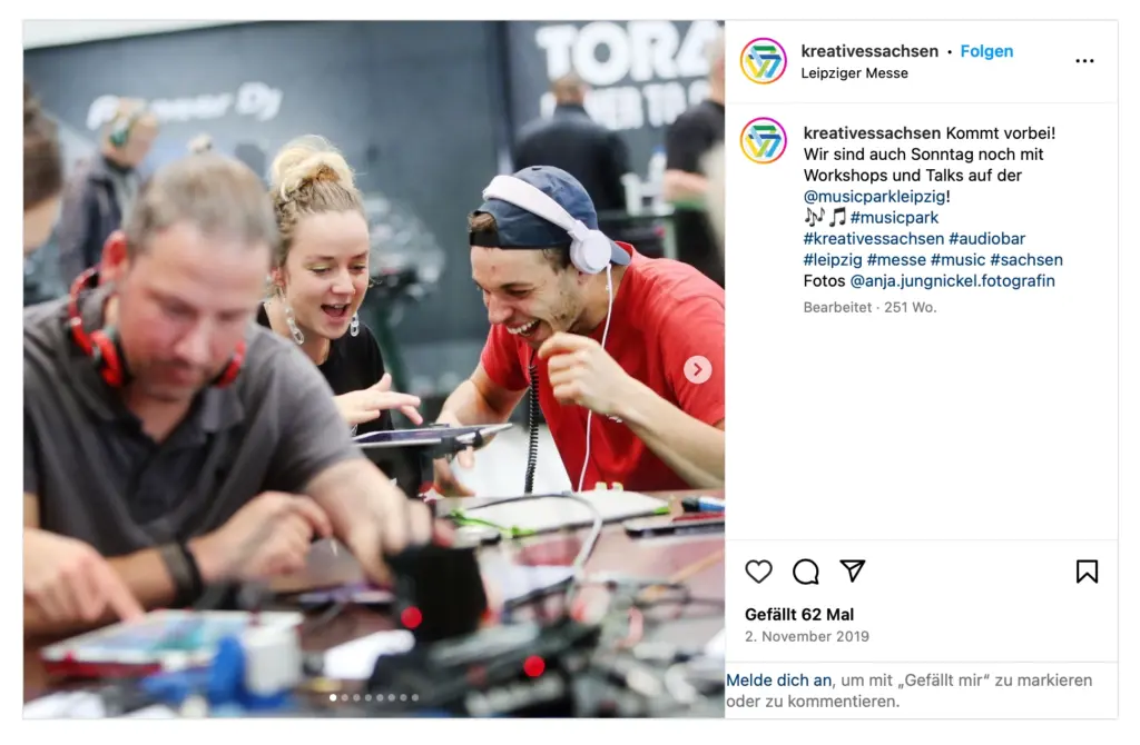 Screenshot eines Instagram-Beitrags des Accounts @kreativessachsen von der Leipziger Messe vom 2. November 2019. Der Beitrag kündigt Workshops und Talks auf dem @musicparkleipzig an und nennt im Text den Fotonachweis "Fotos @anja.jungnickel.fotografin". Das Foto zeigt mehrere Personen, darunter eine junge Frau und einen Mann mit Kopfhörern, die gut gelaunt an Tischen mit technischen Geräten und Tablets arbeiten. Der Beitrag hat 62 Likes.