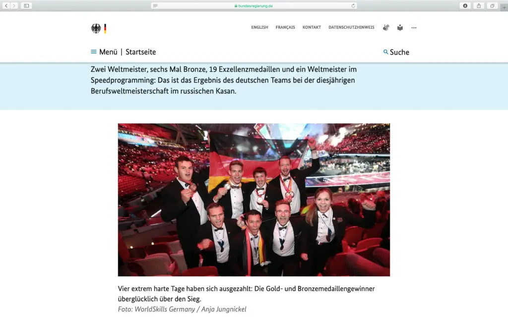 Screenshot der Webseite bundesregierung.de mit dem Text über das Ergebnis des deutschen Teams bei der Berufsweltmeisterschaft in Kasan, darunter zwei Weltmeister, sechs Mal Bronze, 19 Exzellenzmedaillen und ein Weltmeister im Speedprogramming. Im Zentrum steht ein von Anja Jungnickel fotografiertes Bild des überglücklichen deutschen Teams mit Medaillen und einer Deutschlandfahne in einem großen Stadion. Darunter steht der Fotonachweis "Foto: WorldSkills Germany / Anja Jungnickel".