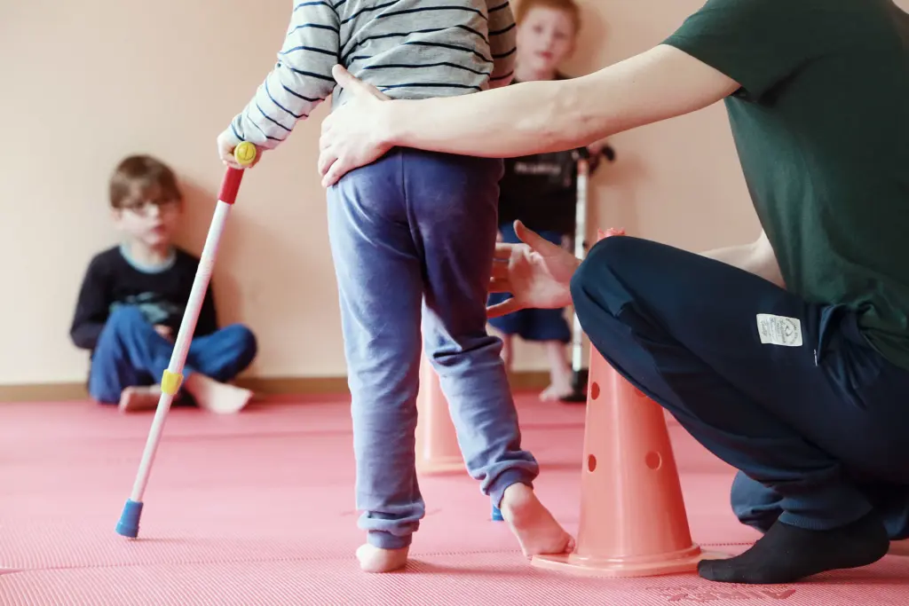 Eine ehrenamtliche Helferin des Ponte Kö e.V. im intensiven Training nach der Petö-Methode mit einem gehbehinderten Kind während einer konduktiven Förderwoche in Weißenfels.