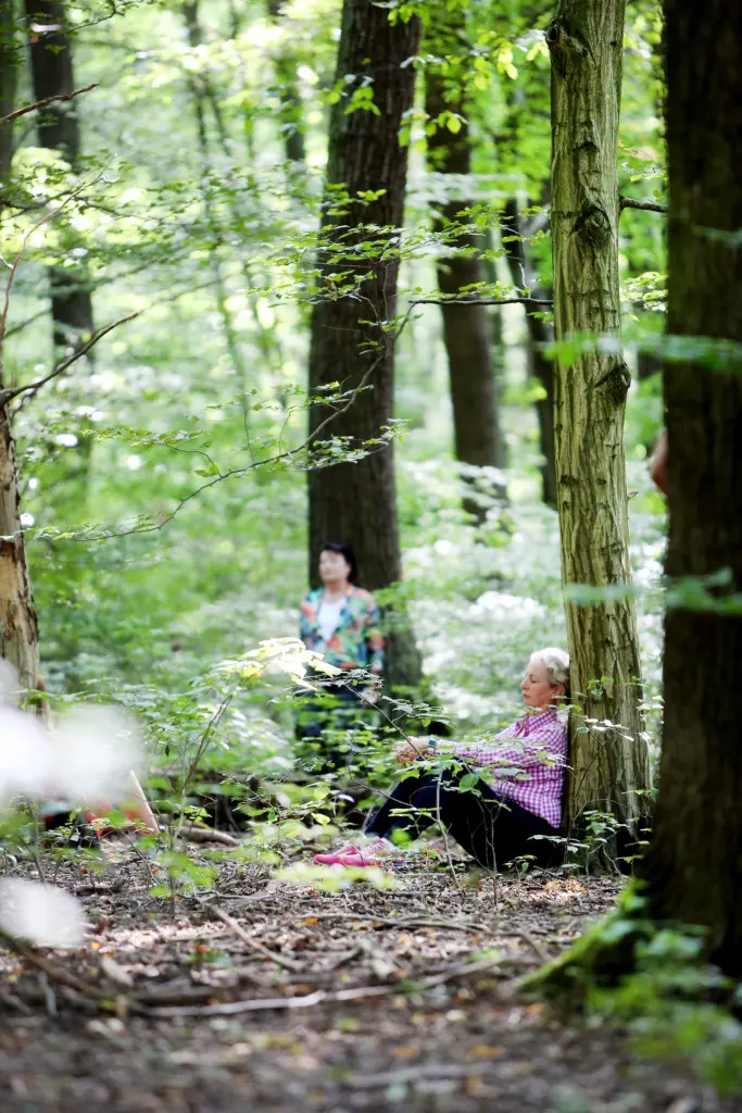 Eine Teilnehmerin sitzt entspannt an einen Baum angelehnt im Rahmen des Waldbadens (Shinrin-Yoku-Methode) im Nationalpark Hainich bei Weberstedt am 12.08.2019. Foto: Anja Jungnickel