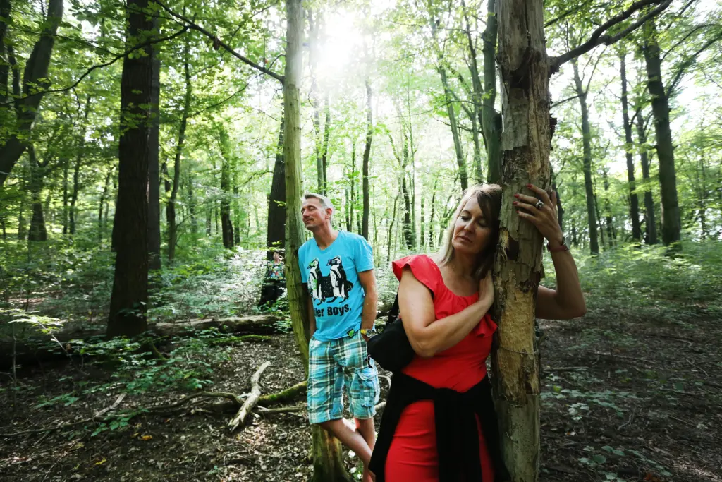 Zwei Teilnehmer lehnen sich mit geschlossenen Augen an Bäume während des Waldbadens (Shinrin-Yoku-Methode) im Nationalpark Hainich bei Weberstedt am 12.08.2019. Foto: Anja Jungnickel
