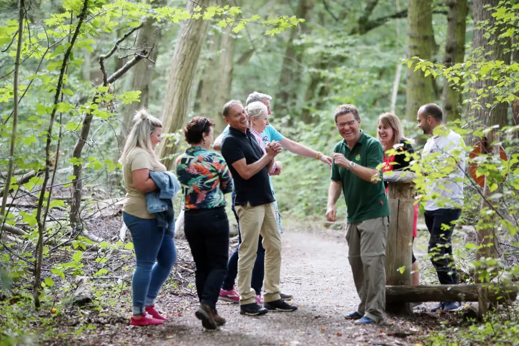 Jürgen Dawo und eine lachende Gruppe von Teilnehmern versammelt auf einem Waldweg beim Waldbaden (Shinrin-Yoku-Methode) im Nationalpark Hainich bei Weberstedt am 12.08.2019. Foto: Anja Jungnickel
