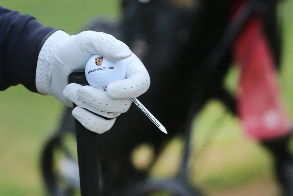 Professionelle Unternehmens- und Eventfotografie von Anja Jungnickel beim Porsche Golf Cup in Machern bei Leipzig: Detailaufnahme eines mit Porsche-Logo gebrandeten Golfballs und Tees in einer Golferhand[cite: 18].