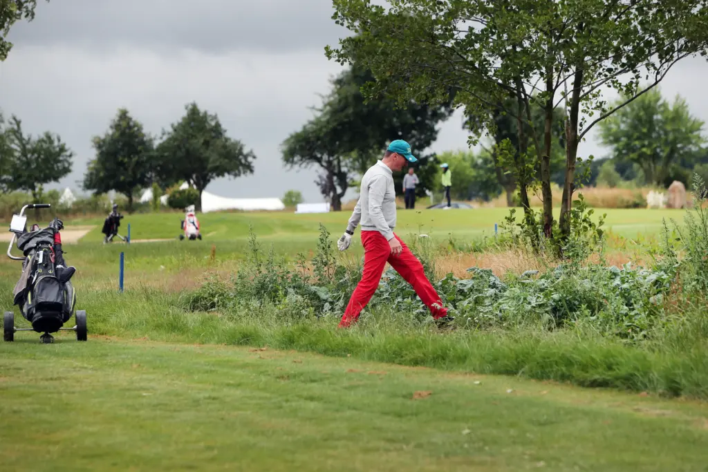 Professionelle Unternehmens- und Eventfotografie von Anja Jungnickel beim Porsche Golf Cup in Machern bei Leipzig: Teilnehmer stehen im Hintergrund bei einem Golfcart auf dem Platz.