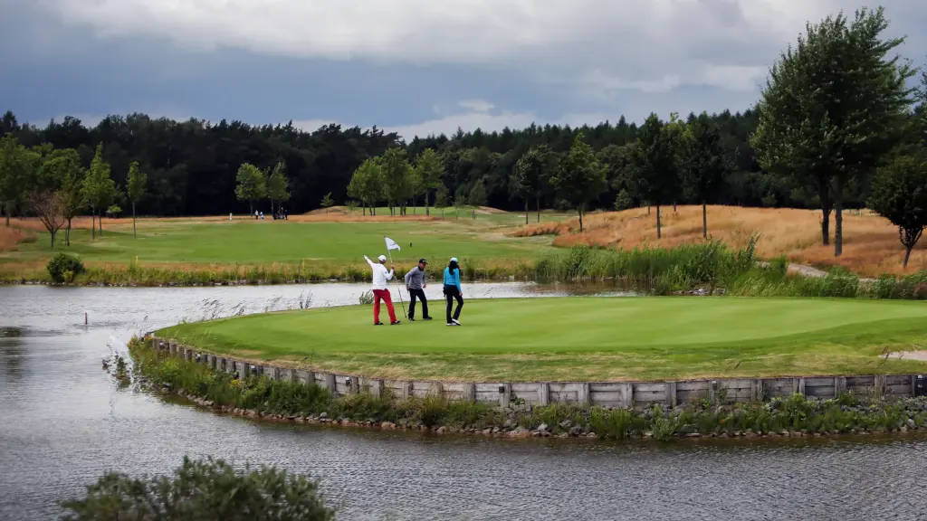 Professionelle Unternehmens- und Eventfotografie von Anja Jungnickel beim Porsche Golf Cup in Machern bei Leipzig: Drei Golfspieler auf einem von Wasser umgebenen Green.
