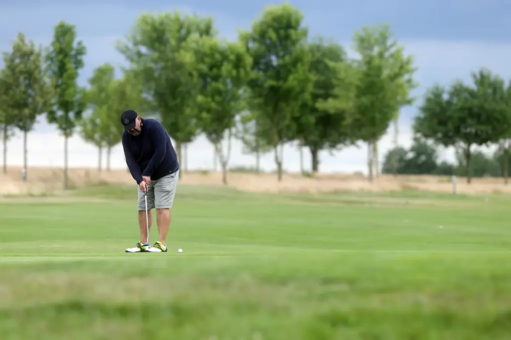 Professionelle Sport- und Unternehmensfotografie von Anja Jungnickel in Leipzig: Ein Golfer konzentriert sich auf dem Grün beim Putten während eines Business-Turniers.