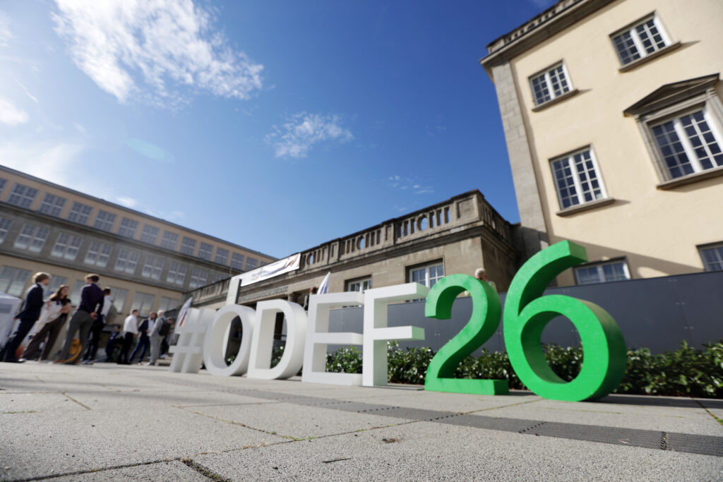 Hochwertige Business- und Eventfotografie vom 15. Ostdeutschen Energieforum in Leipzig, festgehalten von Anja Jungnickel[cite: 19]. Das Bild zeigt eine sympathische, ungestellte Momentaufnahme im Auditorium: Zwei Teilnehmer machen in den Sitzreihen des Hörsaals fröhlich ein Selfie mit dem Smartphone, während im Hintergrund weitere Kongressbesucher zu sehen sind[cite: 19]. Perfekt als Referenz für authentische Eventmomente, Networking und professionelle Unternehmensfotografie[cite: 19].