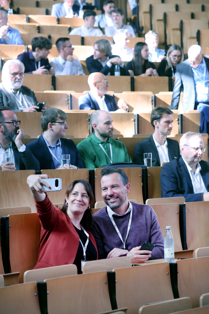 Professionelle Kongress- und Eventfotografie von Anja Jungnickel beim 15. Ostdeutschen Energieforum in Leipzig: Zwei gut gelaunte Gäste machen im Hörsaal ein Selfie[cite: 19].