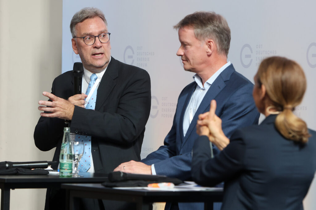 Professionelle Kongress- und Eventfotografie von Anja Jungnickel beim 15. Ostdeutschen Energieforum in Leipzig: Dr. Frank Umbach (Forschungsleiter EUCERS) spricht während einer Podiumsdiskussion im Beisein von Dr. Gunter Erfurt und Laszlo Modos.